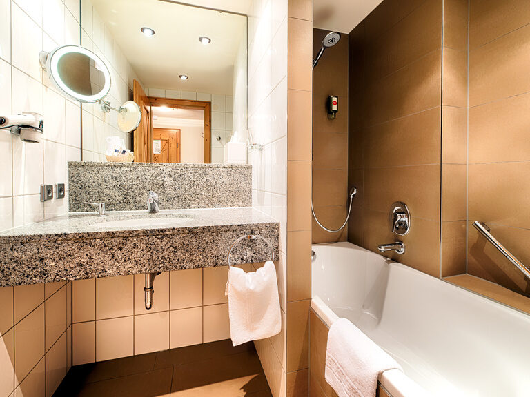 Das elegante Badezimmer mit Badewanne und Spiegel im Komfortzimmer des Landhaus Feckl.