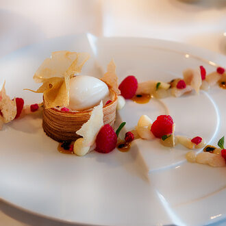 Ein raffiniertes Dessert, sorgfältig auf einem weißen Teller im Sternerestaurant Feckl bei Stuttgart präsentiert.