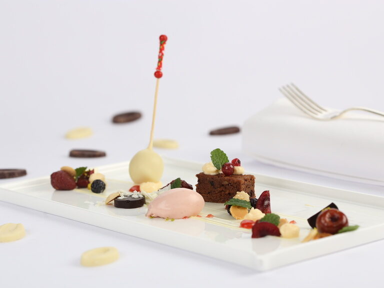 Ein elegantes Dessert auf einem weißen Teller im Hotelrestaurant Feckl präsentiert Gourmet-Kulinarik.
