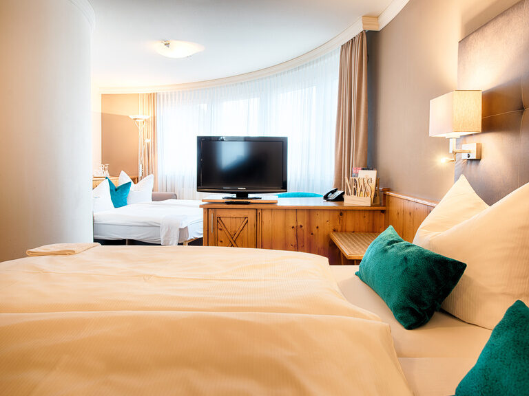 Das geräumige Familienzimmer im Hotel Landhaus Feckl mit großem Bett und Flachbildfernseher.