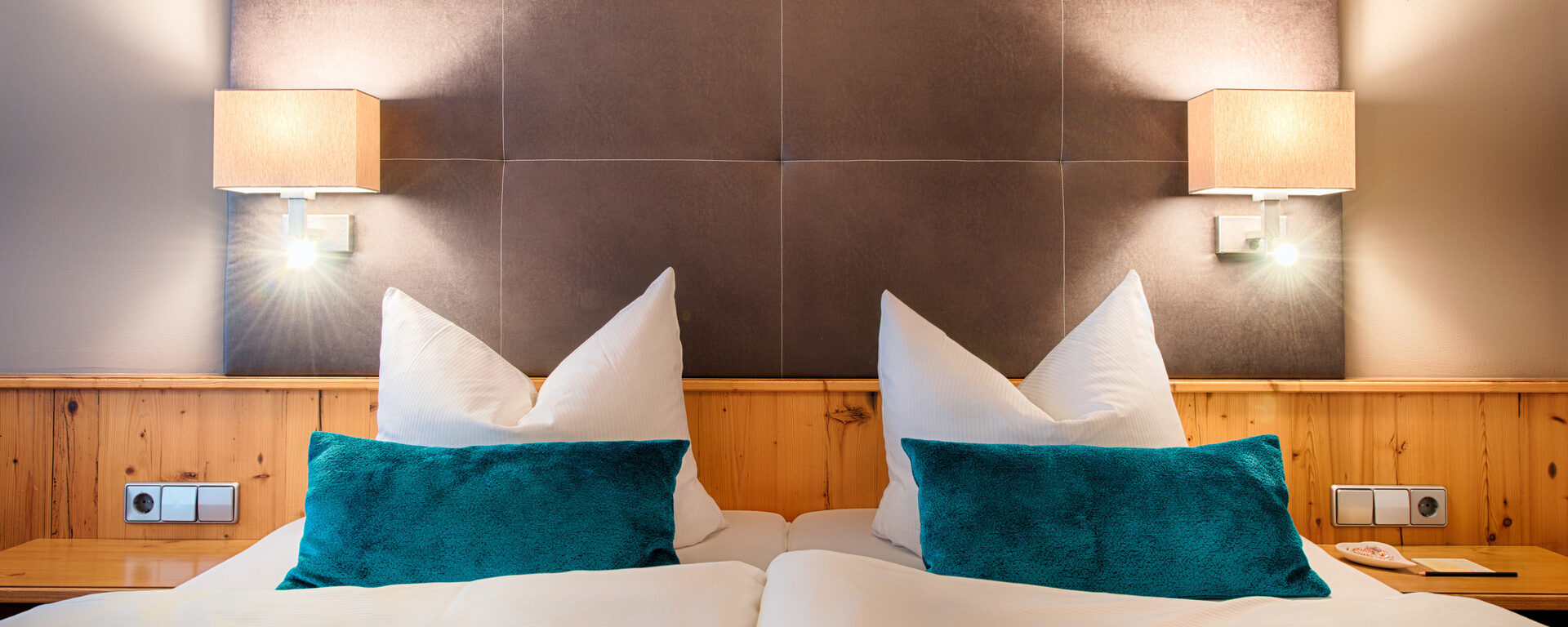 Die gemütliche Schlafzimmerecke im Hotelzimmer mit stimmungsvoller Beleuchtung und großen Bett.