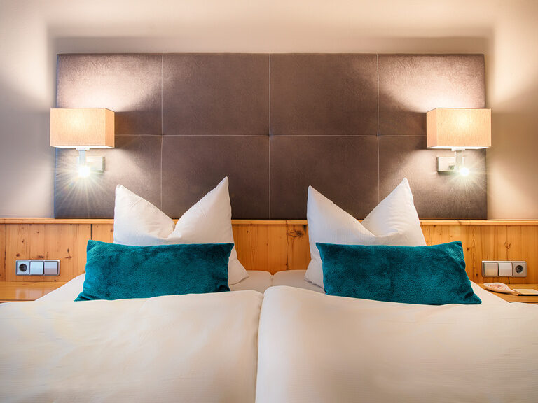 Die gemütliche Schlafzimmerecke im Hotelzimmer mit stimmungsvoller Beleuchtung und großen Bett.