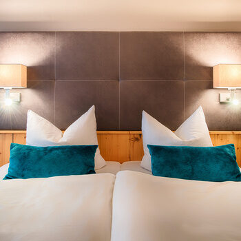 Die gemütliche Schlafzimmerecke im Hotelzimmer mit stimmungsvoller Beleuchtung und großen Bett.