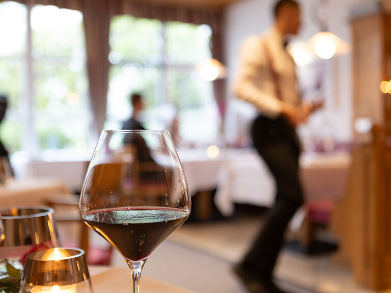 Glas Rotwein mit Person im Hintergrund