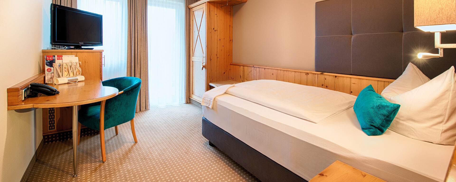 Das komfortable Schlafzimmer im Hotel Landhaus Feckl mit Bett und Schreibtisch.