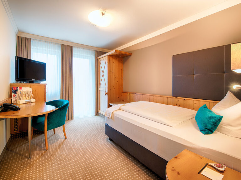 Das komfortable Schlafzimmer im Hotel Landhaus Feckl mit Bett und Schreibtisch.