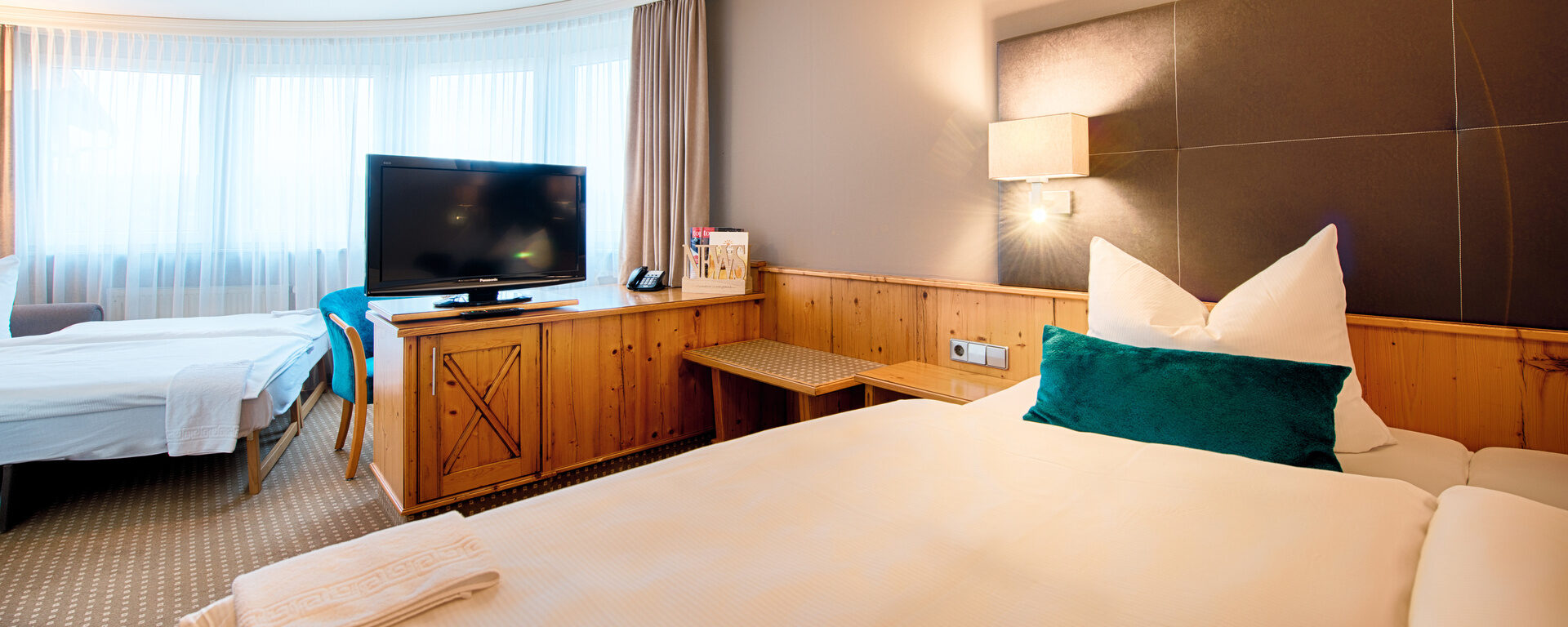 Ein geräumiges Schlafzimmer im Hotel Landhaus Feckl Komfortzimmer mit Bett und Zusatzbett.