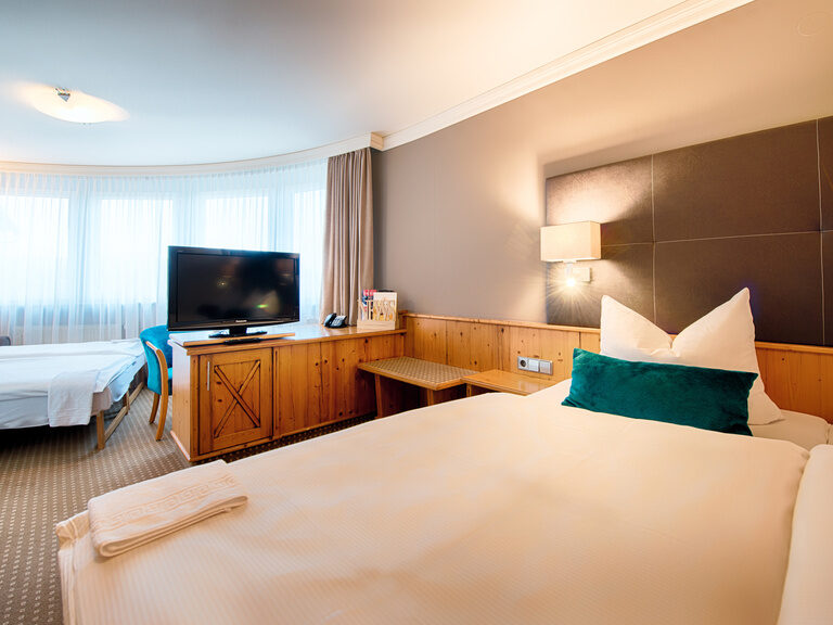 Ein geräumiges Schlafzimmer im Hotel Landhaus Feckl Komfortzimmer mit Bett und Zusatzbett.
