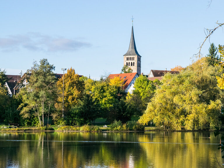 Eine harmonische Landschaft bei Sindelfingen mit spiegelndem Wasserlauf und grünen Uferbäumen.